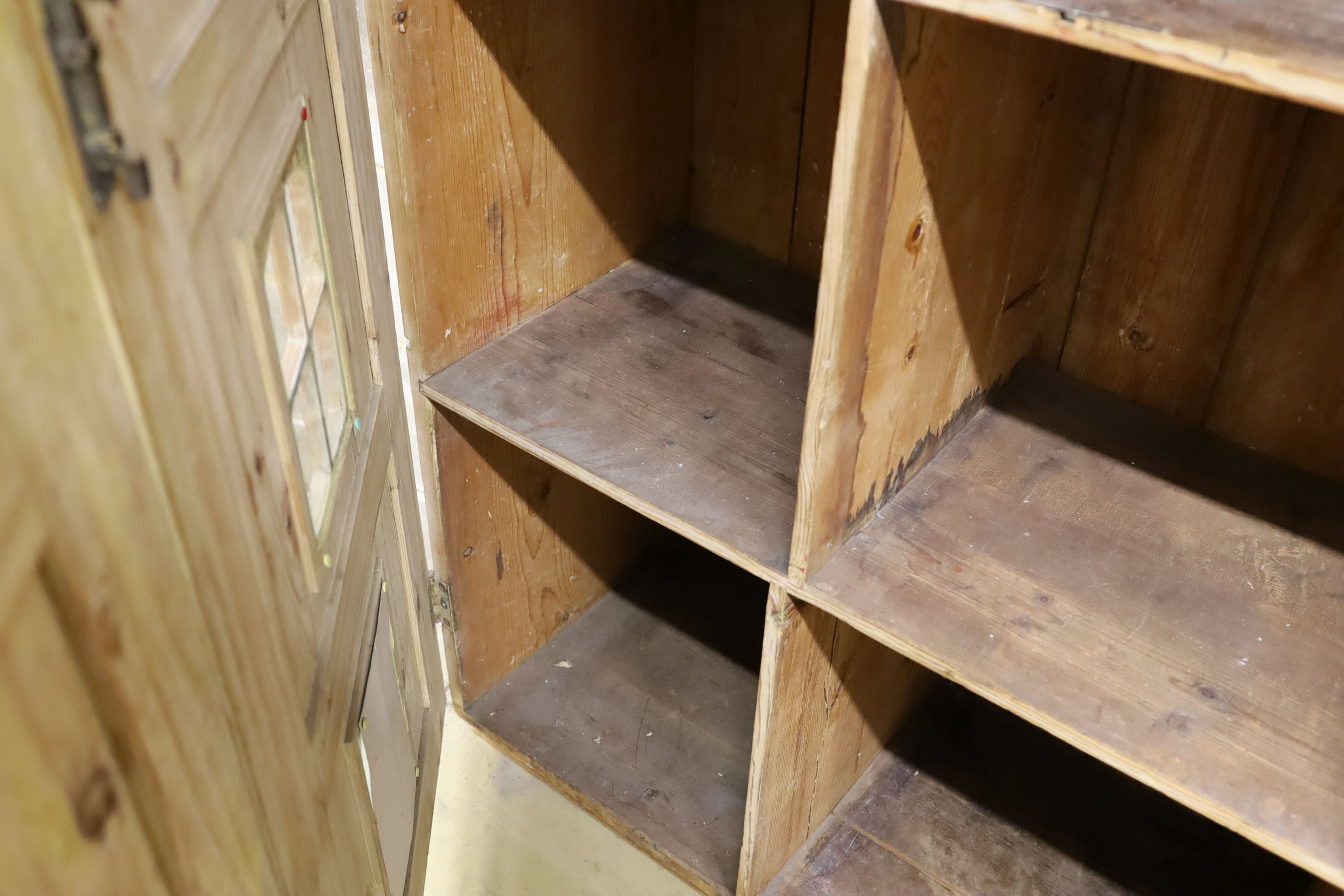 A 19th century stripped pine hall cupboard modelled as a dolls house the two door nine window facade enclosing a compartmented interior, width 182cm, depth 46cm, height 192cm